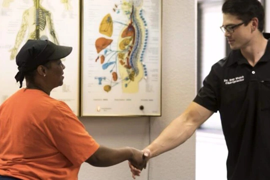 Clinic staff member and patient greeting each other with a handshake